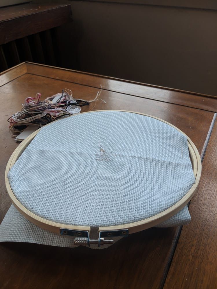 a cross-stitch work in progress on a round frame