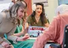Jessi, a United States Air Force veteran, gifts a resident veteran at the Pioneer Home with a 'Pin-Ups for Vets' calendar. Also seen is Melanie, an Army veteran who works with the organizatio