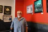 Ken Olson poses for a photo in front of his paintings which are currently on display at Kaladi Brothers Coffee in downtown Wasilla. By Jacob Mann/Frontiersman