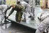 U.S. Marine Corps members with the 3rd Marine Aircraft Wing, Marine Corps Air Station Miramar, Cali., train Air Force Airmen on how to lay AM 2 matting down on damaged flight lines during exe