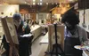 Host artist Lori Teich, dressed up as Bob Ross, leads a group of Artists Uncork'd painters as they attempt the Mexican tradition of painting sugar skulls on canvas Friday evening in Wasilla. 
