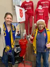 Veteran bell ringers Janet and Ashley Kincaid stand in front of a red kettle. Courtesy photo