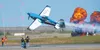 Melissa Burns, in her Edge 540, flies through the uprights her team is holding to cut ribbons during the 2024 Arctic Thunder Open House at JBER. J.David McChesney/File Photo