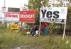 GREG JOHNSON/Frontiersman Sergio Acuña, left, and Derek Musto
work to put up a political sign at the corner of Hering and Main
streets in downtown Wasilla on Friday. The pair are volunteers
s