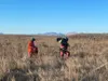 Coast Guard Air Station Kodiak personnel walk through a field carrying an 8-month-old puppy named Grace, who was rescued after her owner's ship ran aground near Black Point in Kodiak, Alaska,