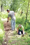 Sheri Friedman, and Sean Cone, volunteers with Lifetree Adventures, work to clear undergrowth and spread soil on the planned nature trail Tuesday near the Valley Community Recycling Solutions