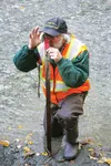 Wasilla Soil &amp; Water Conservation District Executive Director Chuck Kaucic demonstrates taking the slope of the stream by looking between two wooden stakes using a tool that allows him to