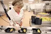 Kathy Green fills vegetable trays with ranch dressing Thursday at the Kurtis Arcala Nutrition Services Center in Palmer. The facility cranks out 2 million meals annually for 35 schools in the