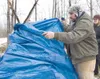Wasilla resident Eric Wolford wraps a tarp around a makeshift
emergency shelter as part of a survival game at Saturday's North
American Outdoor Institute's survival class at Fox Run Lodge and