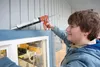 Keegan Halsey caulks around the trim of the new drive-thru coffee window Saturday morning at Gathering Grounds, the coffee shop that is part of the MY House charity for homeless teens. Halsey