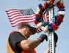 Kevin Burke of Burke's Military and Flags hangs a patriotic wreath on a Mat-Su Veterans' Highway sign near the intersection of Church and Seldon roads in Wasilla on Thursday, May 26, in prepa