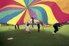 A group of kids run underneath a giant rainbow-colored parachute during the Fall Family Fling and Home Educator Fair at AT&amp;T Sports Center Saturday afternoon. ROBERT DeBERRY/Frontiersman.