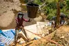 U.S. Space Force Master Sgt. Hanh Le, a Defense POW/MIA Accounting Agency (DPAA) recovery team linguist, prepares to catch a bucket during a DPAA recovery mission in Quang Nam Province, Vietn