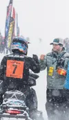 Iron Dog veteran Tyler Aklestad bumps his fist with a race official during the 2026 Iron Dog start. J. David McChesney/Frontiersman