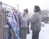 K.T. McKEE/Frontiersman Jenny Beebe helps property manager and
potential customer Jay Metz with sizing on a pair of camouflage
pants as snow covers dozens of racks of clothes and other items
