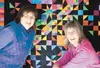 Friends Patricia Ott and Rene Russ pose in front of a quilt they made together to raffle as a benefit for the Cystic Fibrosis Foundation and the Mat-Su Miners. HEATHER A. RESZ/Frontiersman