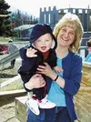 Eight-month-old Joseph reaches for the camera while Lynn
Stachelrodt holds him. Stachelrodt says she becomes quite attached
to the infants she cares for at the Children's House. Photo by
EOWY