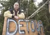 Chickaloon resident Charles Lone Wolf stands with a detour sign he put up on East Chickaloon Branch Road near his driveway. He is rerouting truck traffic through his driveway in an attempt to