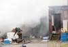 Smoke fills the air as propane tanks are carried out of a burning house on N. Moose Meadows Lane Thursday. ROBERT DeBERRY/Frontiersman