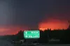 MATT TUNSETH/Frontiersman As the sun sets in the background, a
lightning-caused wildfire west of the Susitna River sends a column
of smoke skyward early Thursday morning north of Houston. Two