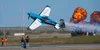 Melissa Burns, in her Edge 540, flies through the uprights her team is holding to cut ribbons. J. David McChesney/Frontiersman