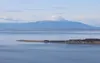 Wind turbines spin at a development at Fire Island, just offshore from Anchorage. Mount Susitna, or Dghelishla, is in the background.  Nathaniel Herz/Northern Journal