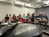 Members of the men’s chorus of Seven Brides for Seven Brothers listen to Vocal Director Carrie Johnson during a musical rehearsal. Courtesy of Seims Theatre Productions