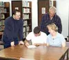 Zac Forsyth signs a letter of intent Monday in the Palmer High
School library to attend the University of Alaska Fairbanks.
Watching him sign are Palmer boys' basketball coach Brandon Blake,
