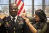Maj. Tatchie Manso, 1st Theater Sustainment Command, smiles as Elena, Manso's wife, pins on his new rank during a ceremony at Fort Knox, Ky., Dec. 11, 2019. The Army recently initiated change