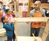 Alivia, 9, and Lillian Matthews, 10, get help building their lemonde stand from Home Depot associate Alex Mariano Saturday morning in Wasilla. ROBERT DeBERRY/Frontiersman.com