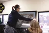 Palmer High School International Baccalaureate (IB) art student Aunesty Loyer, right, helps classmate Sarah Munro hang her (Loyer's) chalk pastel drawing on a wall in Magpie Clothing Exchange