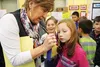 Fifteen-year Sherrod Elementary School teacher Charlotte Ray signs the blue ribbon of one of her third-graders, Reeslynn Lawton, at the school's annual science fair on Thursday, Oct. 15. Ray 
