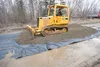 Crews with Northern Asphalt put down an underlayment and then spread gravel on top in an effort to make Stacy Street drivable Monday afternoon. ROBERT DeBERRY/Frontiersman.com