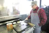 ROBERT DeBERRY/Frontiersman Bob Bowers flips some flap jacks on
the flat iron grill inside the Midnight Fryer’s fully operational
kitchen. The Midnight Fryer is capable of barbecuing a whole 