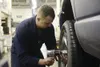 Senior Airman Brian Sanchez, a 732nd Air Mobility Squadron aircraft services specialist, removes a tire from his vehicle at the Automotive Skills Center on Joint Base Elmendorf-Richardson, Fe