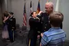 Chief Warrant Officer 5 Brian Brooks looks on as Chief Warrant Officer 5 Teresa Domeier, the command chief warrant officer of the Army National Guard, and his son, Noah, pin his rank to his u