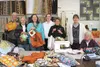Members of a Wednesday sewing group at Just Sew in Palmer pose for a photo with Lt. Lisa Davey from the Salvation Army and a few of the 150 shopping bags and potholders they sewed to give awa