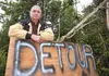 Chickaloon resident Charles Lone Wolf stands with a detour sign he put up on Chickaloon Road near his driveway last July. ROBERT DeBERRY/Frontiersman