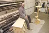 Alaska Log Furnishings' Chad Stuber sits on one of his Chest of Drawers inside his Valley shop. Robert DeBerry