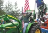 Dr. Joanne Rehn of All Creatures Veterinary drives a John Deere tractor and waves to the crowd during Thursday's Fourth of July Parade in Wasilla. GREG JOHNSON/Frontiersman