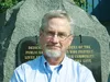 Palmer Director of Public Safety Jon Owen sits in front of the memorial outside the Palmer Police Department building for a photo after being named to the Alaska Seismic Hazards Safety Commis