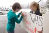 ROBERT DeBERRY/Frontiersman Palmer residents Katie Stark, 15,
left, and Heidi Hanna, 14, put the finishing touches on a ‘Go Kevin
Snavely’ sign before the start of Saturday’s state swimming
c