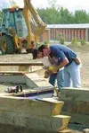 Jeremy Favor, from the Point MacKenzie Rehabilitation Center
[PMRC], inserts a plug on a wooden bench that will surround the
U.S. Flag at Wasilla's Armed Forces Honor Garden. Photo by SCOTT
C