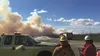 Forestry and local firefighters watch as a plume of smoke rises from a fire along Miller's Reach Road. Officials planned no evacuations in connection with the fire, which ignited an area prev