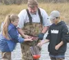 Fifth-grader Victoria Colee of Larson Elementary School helps
Fritz Kraus of ADF&amp;G to rub the milt out of a male salmon and
into a jug of eggs, held by Teeland Middle School seventh-grade