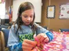 Belle Baca, 9, ties knots in the fringes along the edge of a fleece blanket during a community service project to benefit The Children’s Place Friday afternoon at Sherrod Elementary School in
