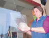 Diane Krauszer holds the rock someone tossed through a window at
the Treasure Loft Thrift Store last week. Photo by STEVE
KADEL/Frontiersman.
