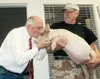 GREG JOHNSON/Frontiersman Al Hummel of Chugiak holds Bacon while
Bob Jones, state conservationist for the Natural Resources
Conservation Service in Palmer, puckers up and plants a kiss on
Bac