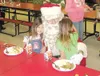 GREG JOHNSON/Frontiersman Sisters Audrey Coon, 5, left, and
Clarissa Coon, 7, hug Santa Claus Tuesday while attending the
annual Christmas Day Dinner at Wasilla High School.