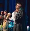 After receiving his diploma from Principal Tyler Gilligan, Valedictorian Taval Dyer is directed to look to the school's photographer for his official picture at Knik Charter's 2024 Graduation